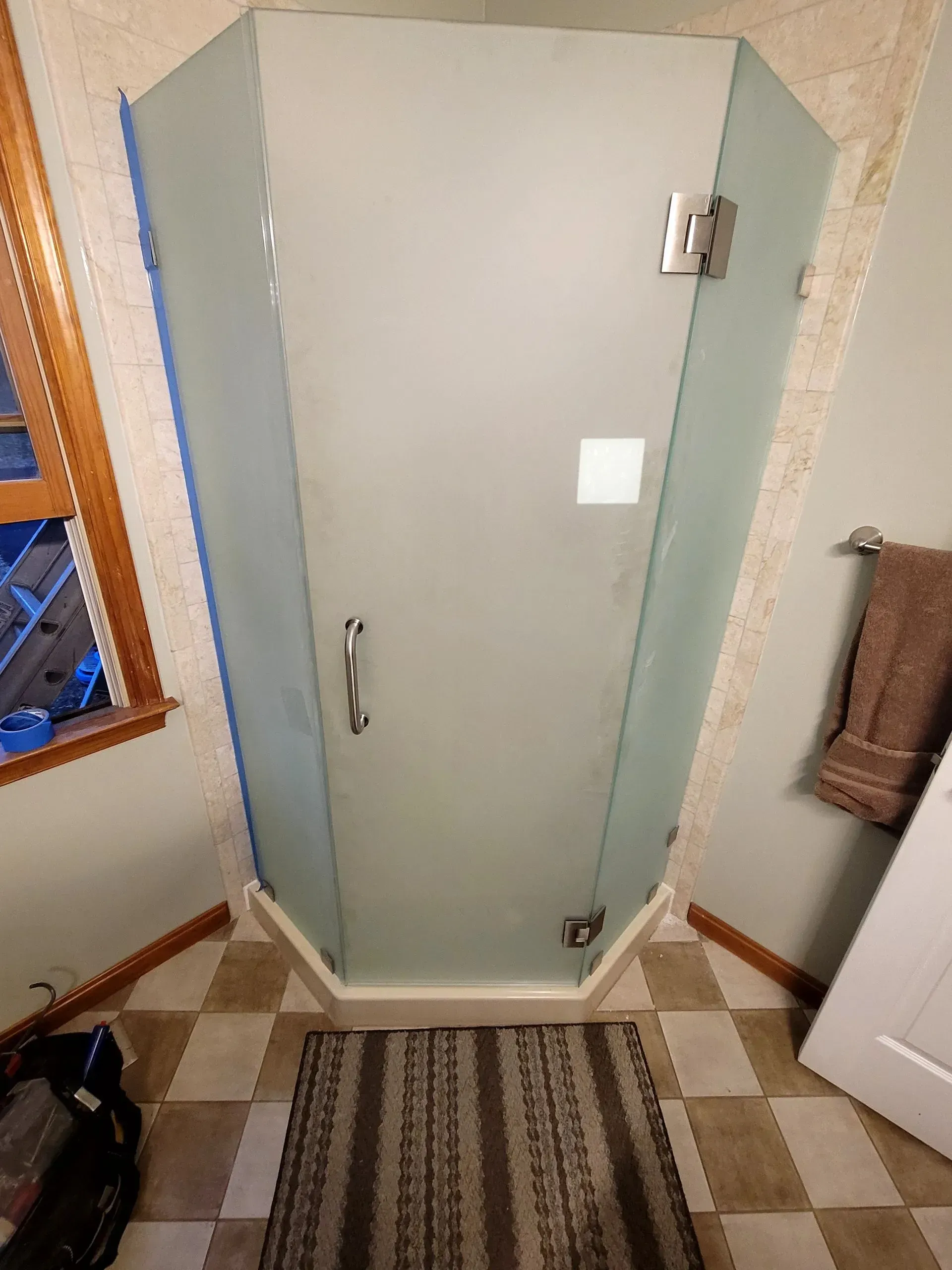 A bathroom with a glass shower door and a rug on the floor.