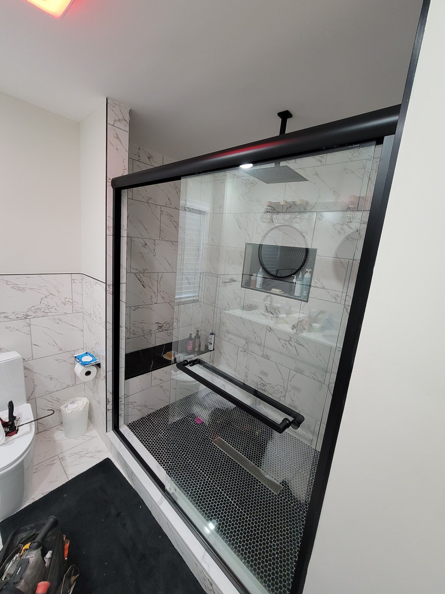 A bathroom with a sliding glass shower door and a toilet.