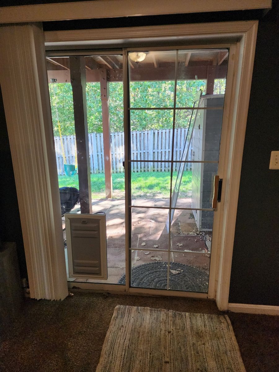 Sliding glass door with pet door, leading to a backyard patio and green lawn.