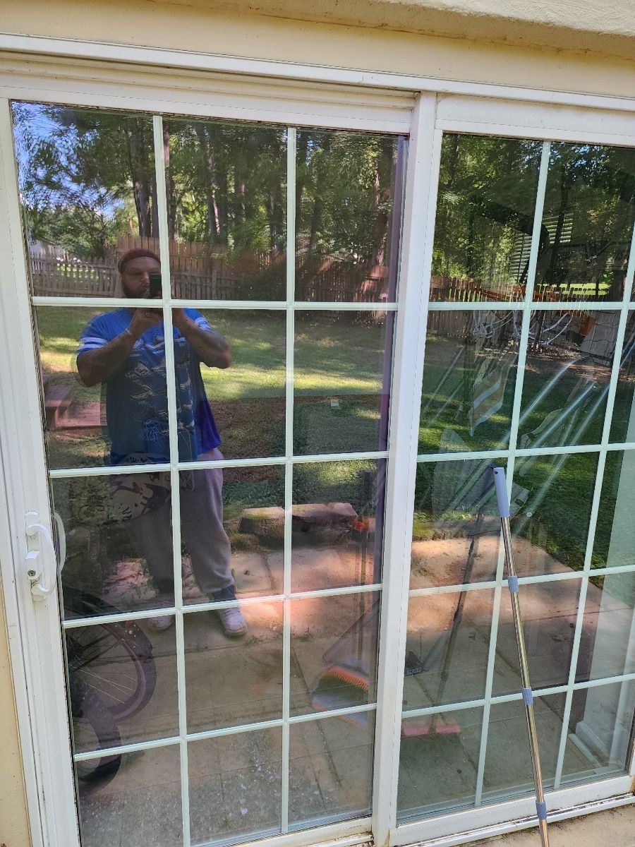 Man reflected in a sliding glass door. He's outside on a patio. White grid pattern on glass.