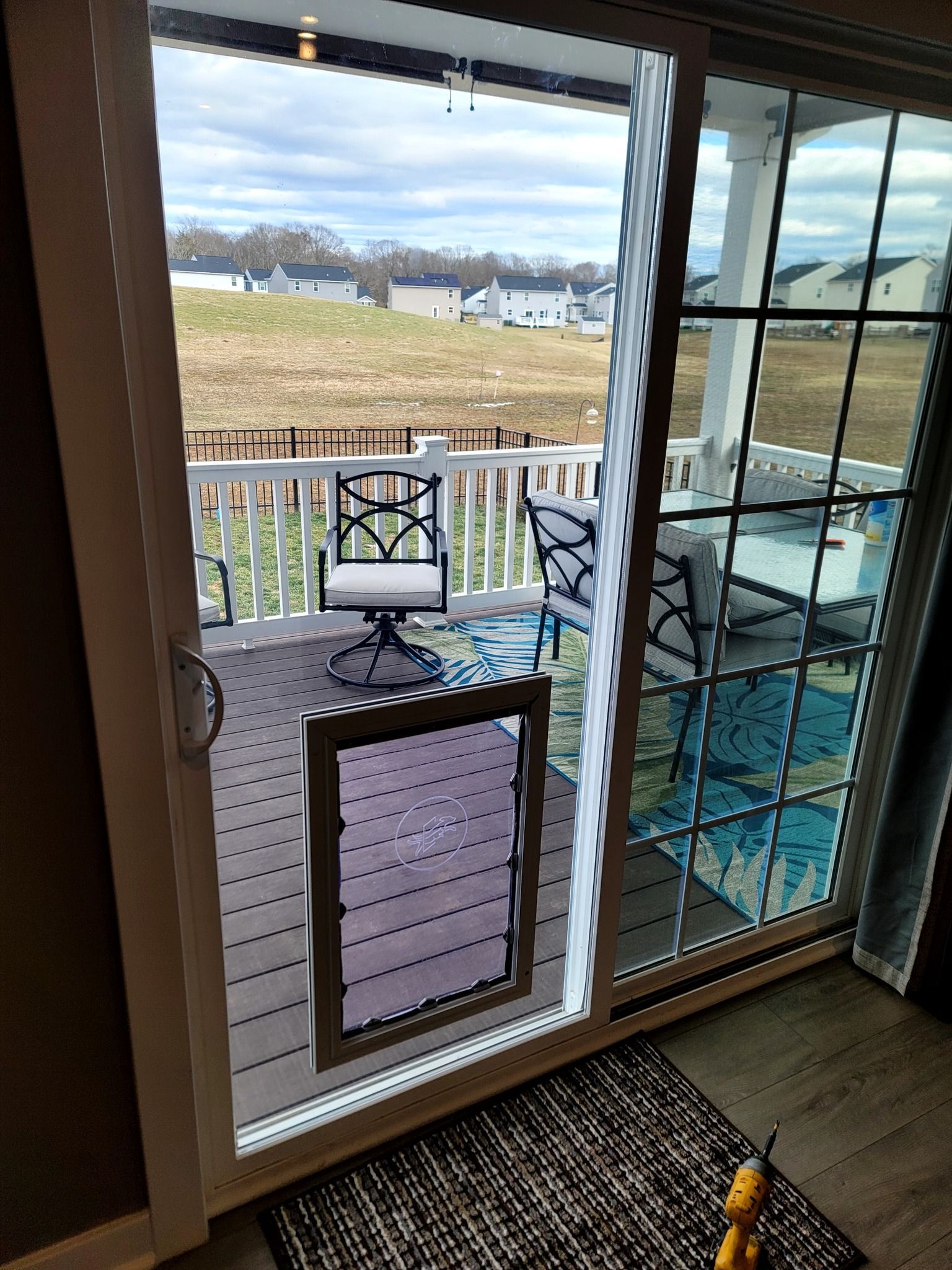A sliding glass door leading to a deck with chairs and a table.