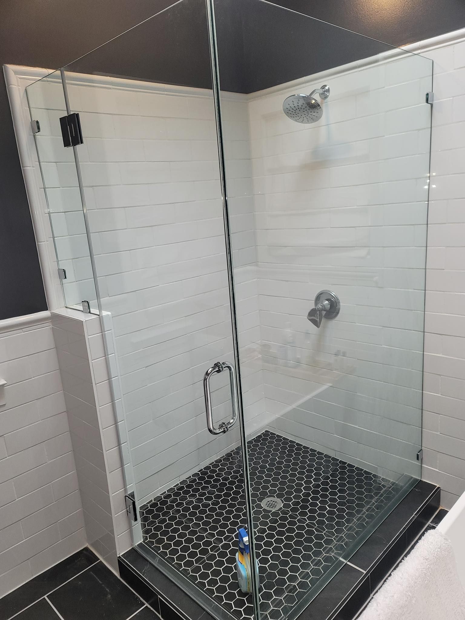 A bathroom with a walk in shower with a chain hanging from the door.