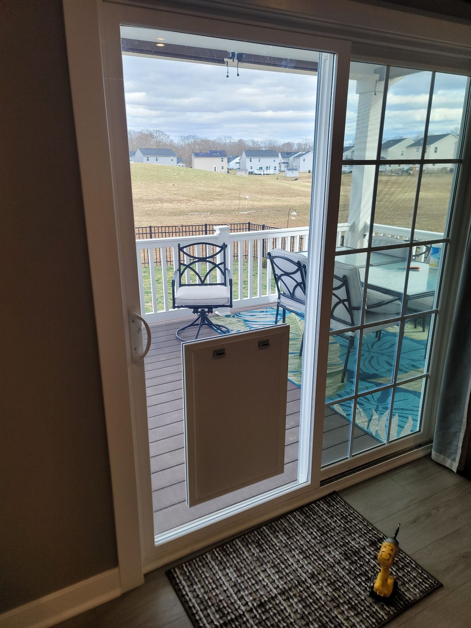 A sliding glass door leading to a deck with a dog door.