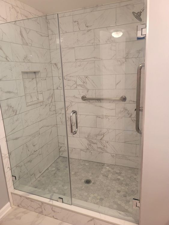 A bathroom with a walk in shower with a glass door.