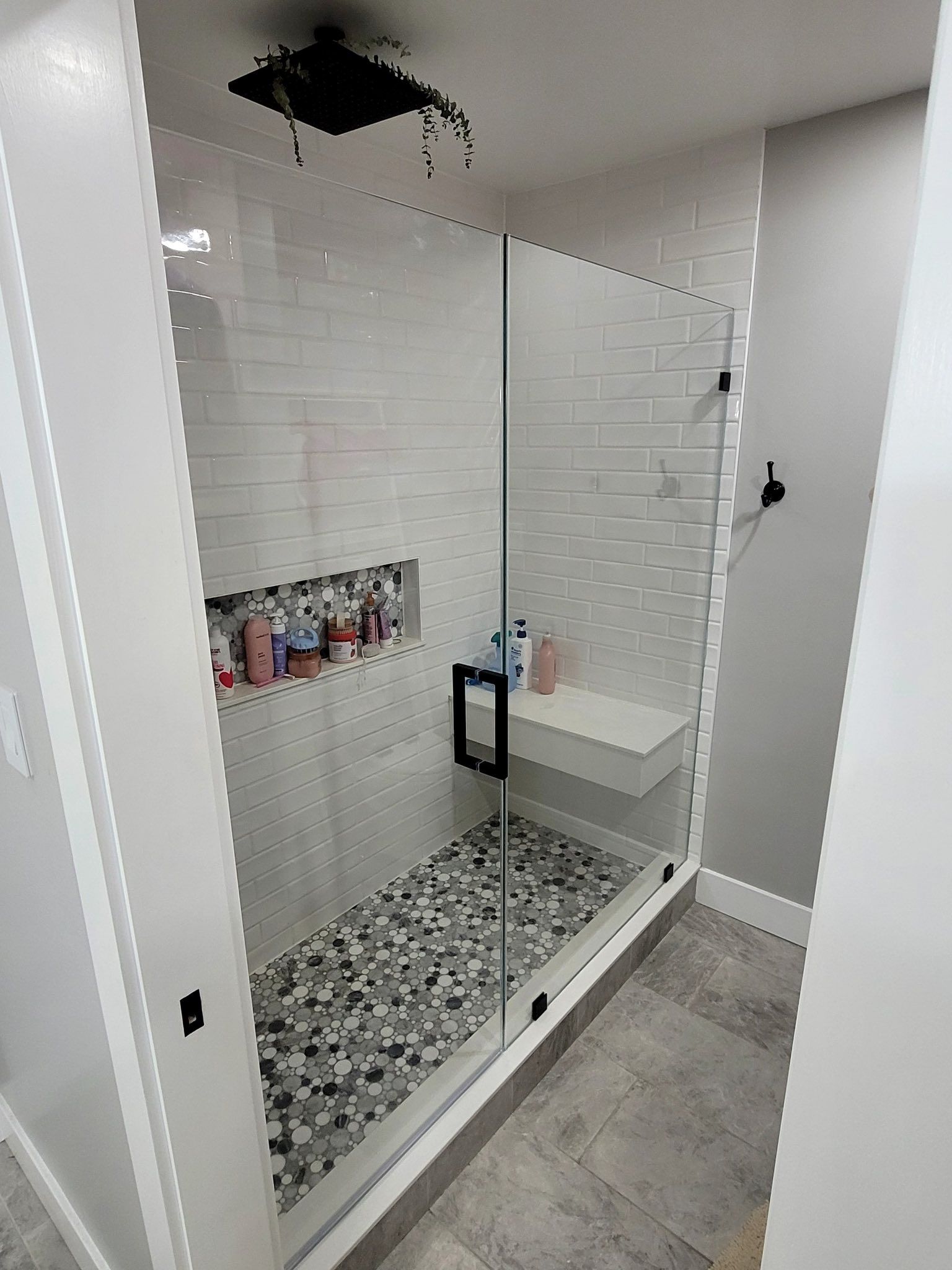 A bathroom with a walk in shower with a glass door.