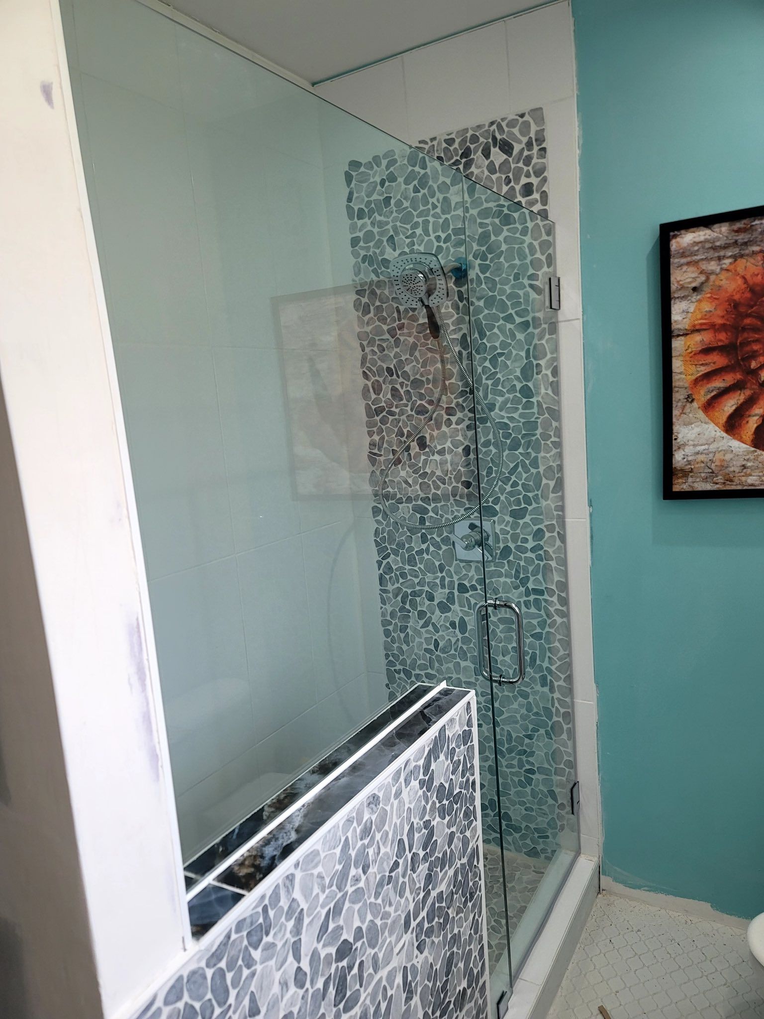 A bathroom with a walk in shower and a picture on the wall.