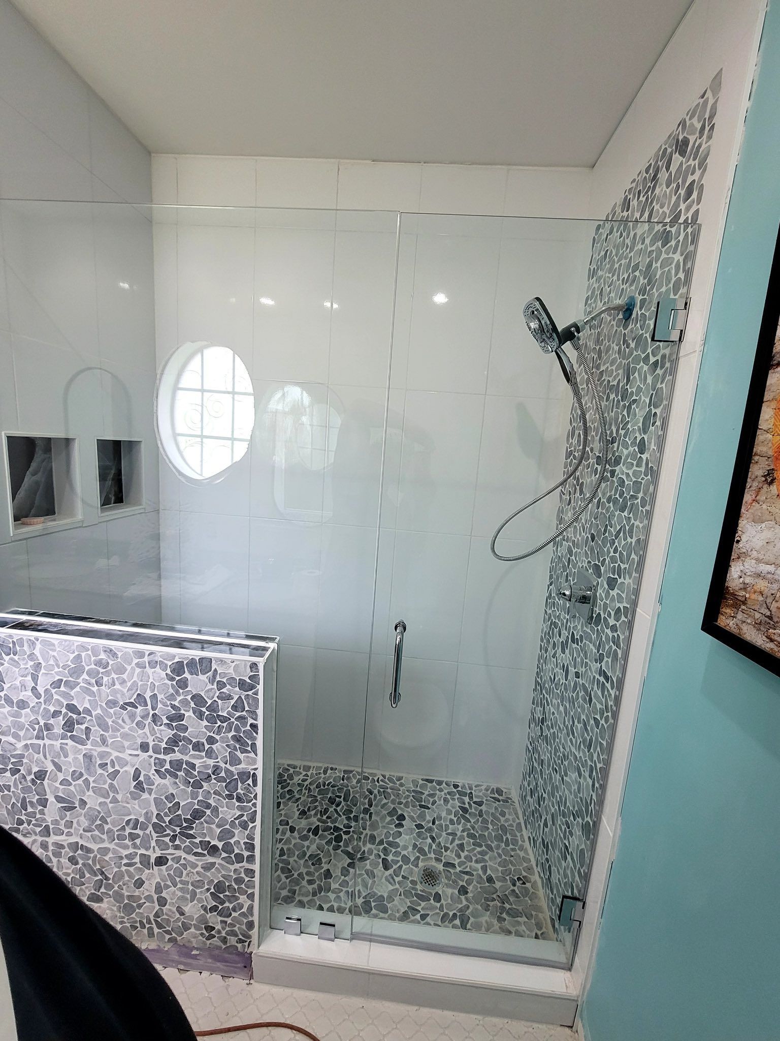 A bathroom with a glass shower door and a picture on the wall.