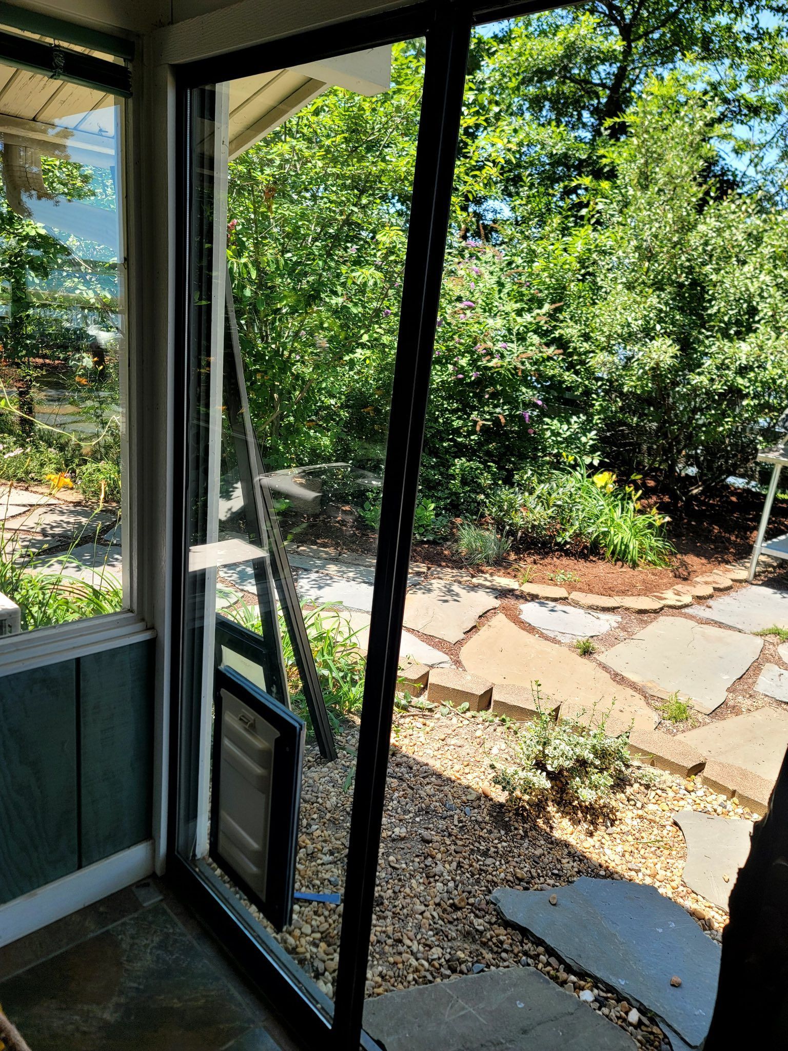 A sliding glass door is open to a patio with trees in the background.