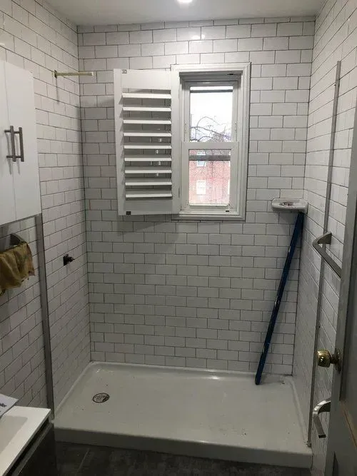A bathroom with a walk in shower and a window.