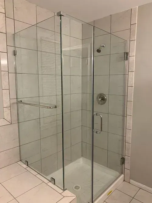 A bathroom with a walk in shower with a glass door.