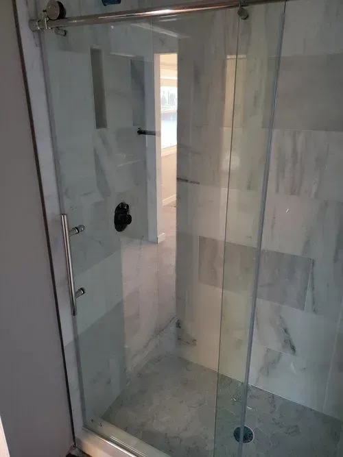 A shower stall with a sliding glass door in a bathroom.