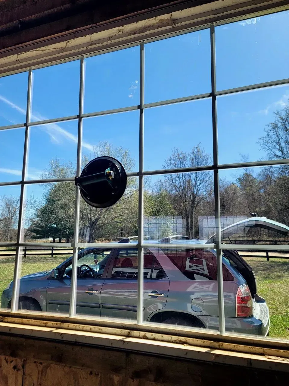 A car is parked in a field behind a window.