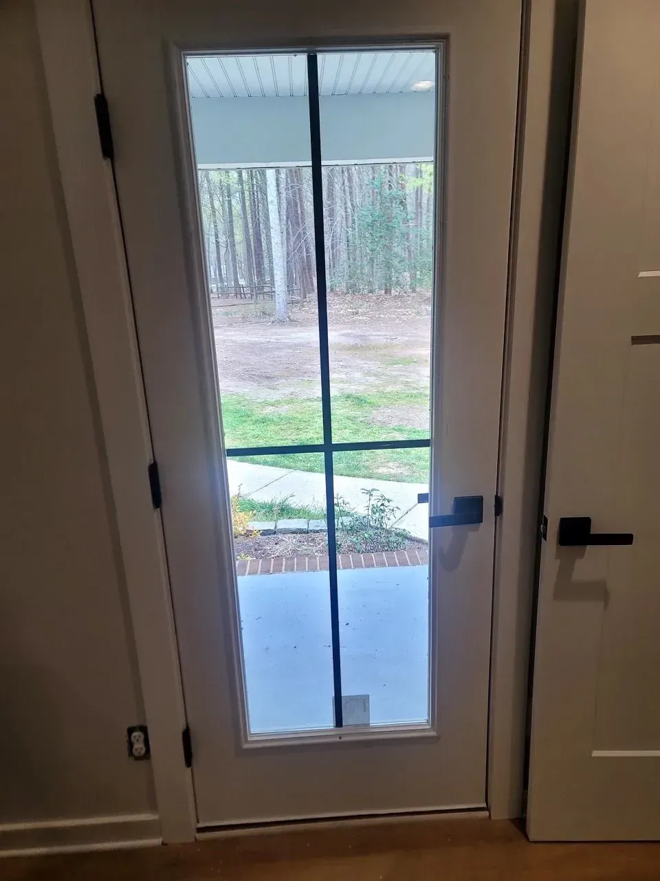 A white door with a window and a black handle in a room.