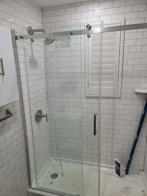 A bathroom with white brick walls and a sliding glass shower door.