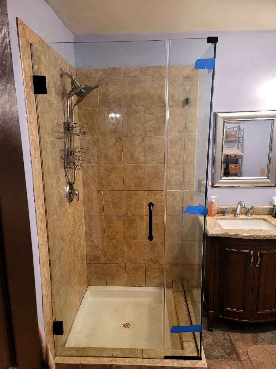 Shower enclosure with glass door and tile walls; bathroom vanity visible.
