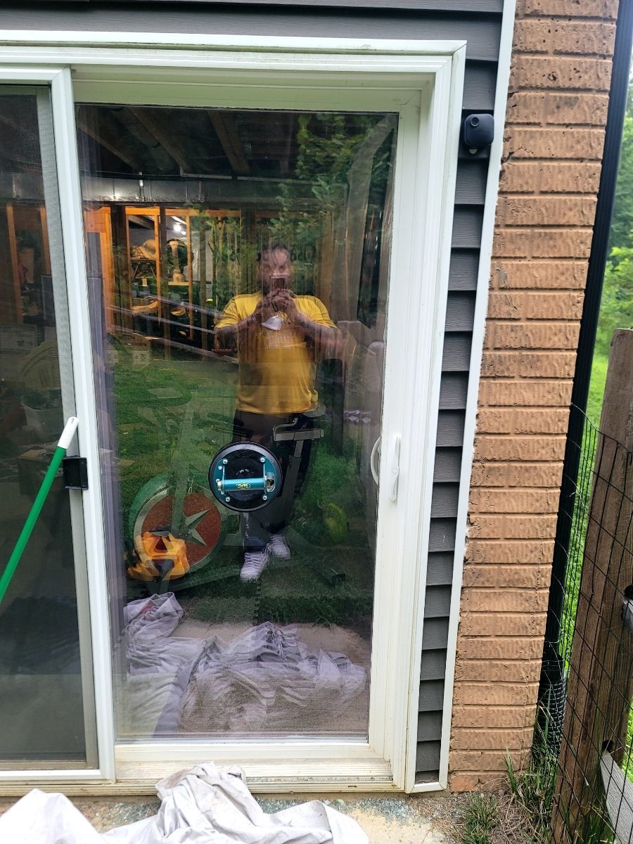 Person taking photo reflected in a sliding glass door. A grassy yard is visible.