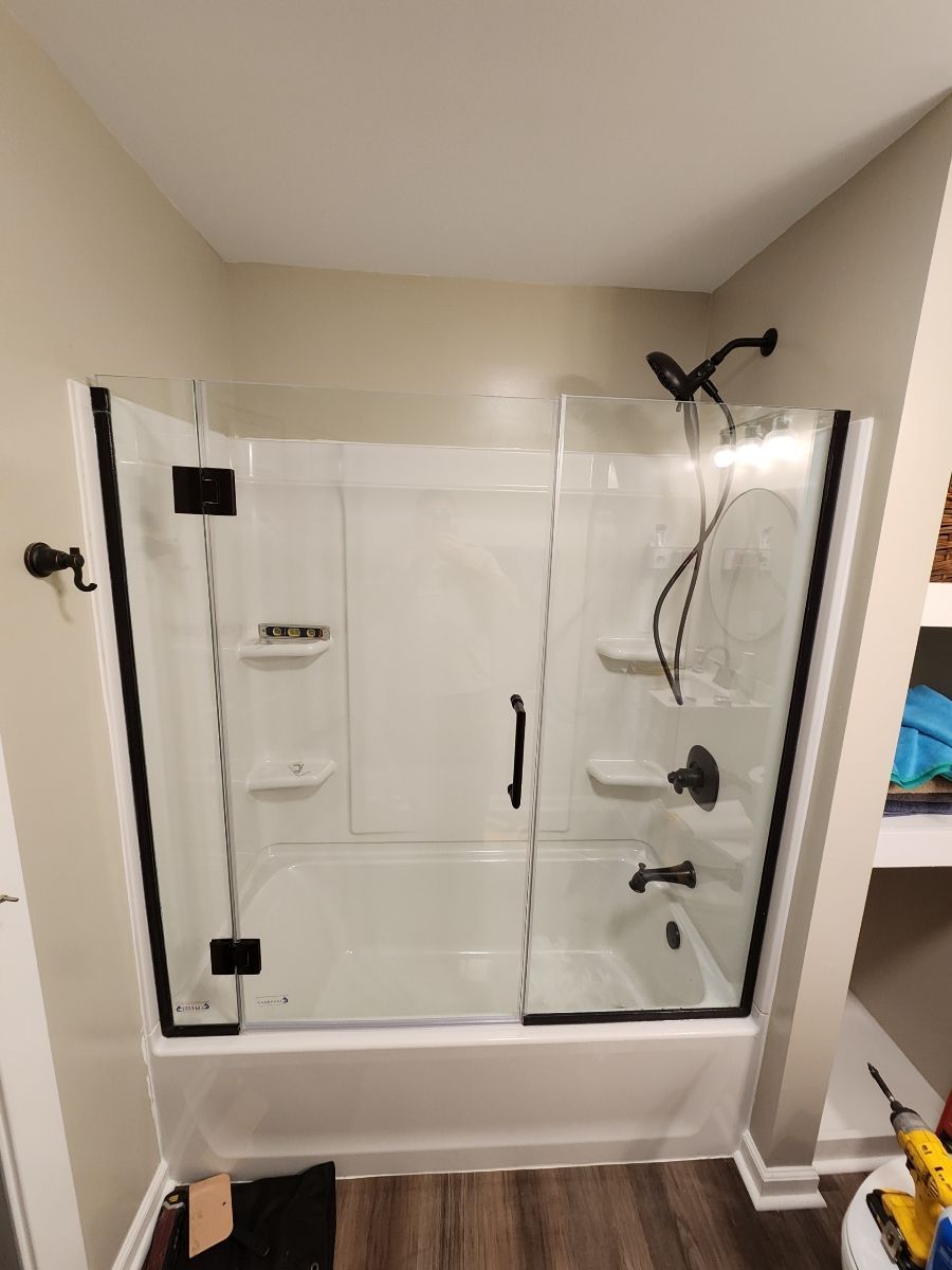 A bathroom with a walk in shower and a glass door.