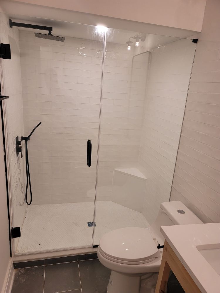 A bathroom with a toilet , sink , shower and glass door.