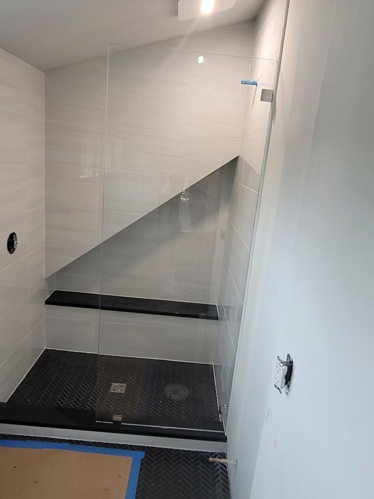 A bathroom with a walk in shower with a glass door.