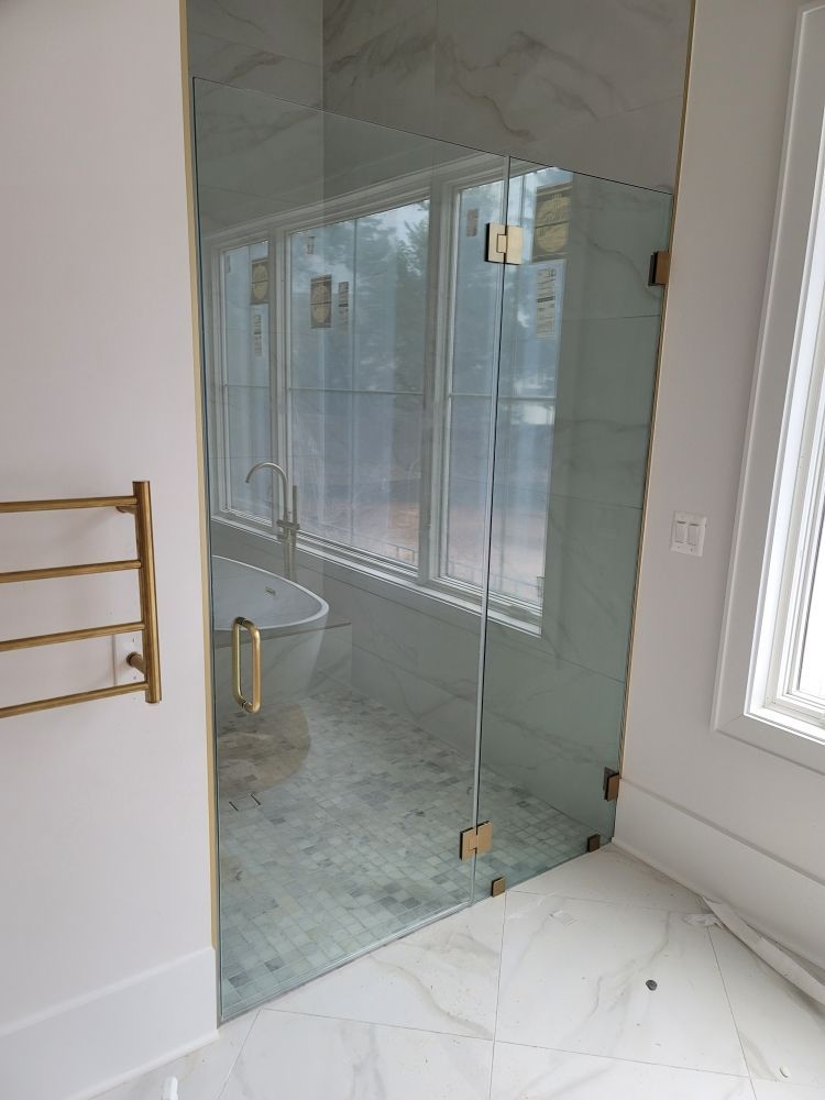 A bathroom with a glass shower door and a bathtub.