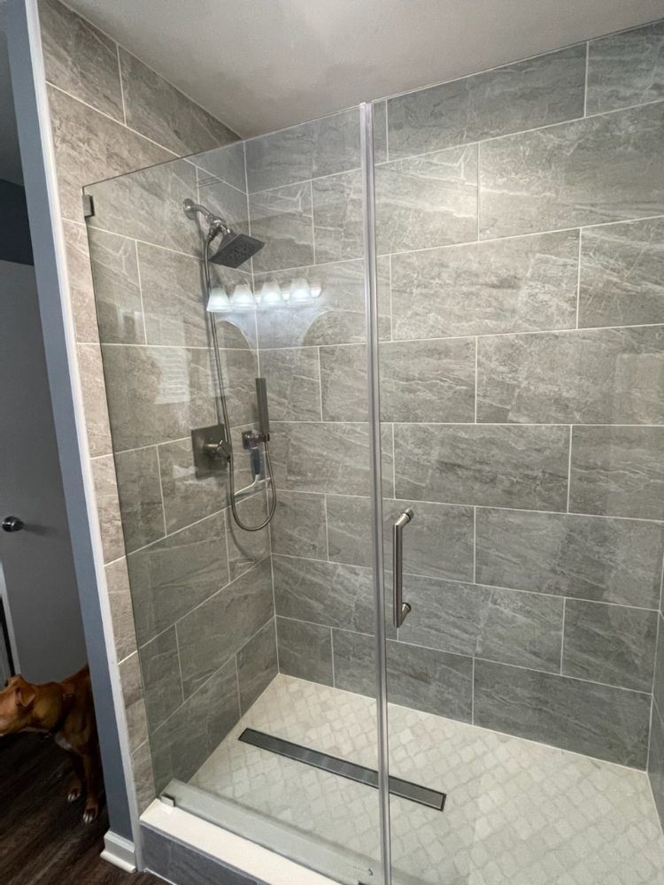 A bathroom with a walk in shower with a glass door.
