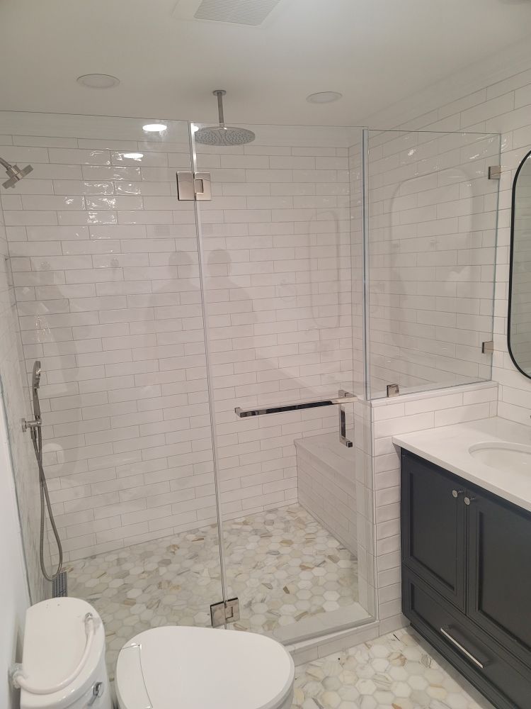 A bathroom with a walk in shower , toilet , sink and mirror.