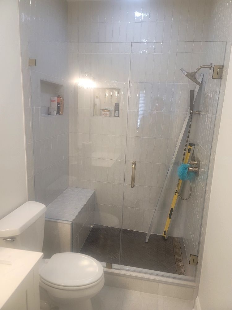 A bathroom with a toilet , sink and shower with a glass door.