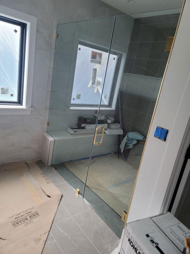 A bathroom with a glass shower door and a window.