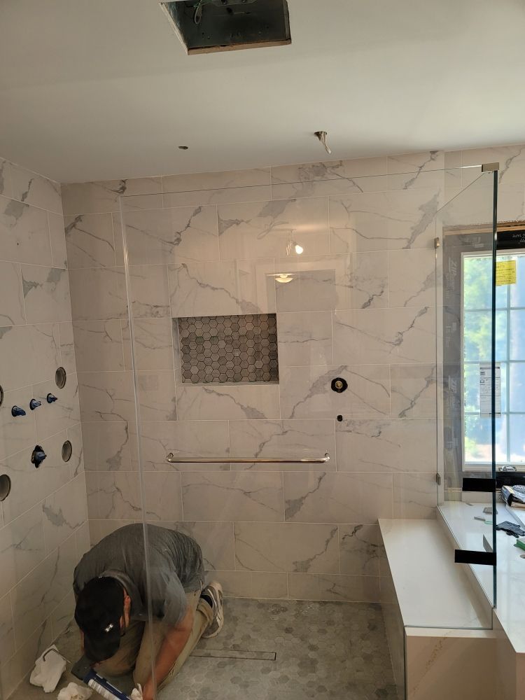 A man is kneeling on the floor in a bathroom.