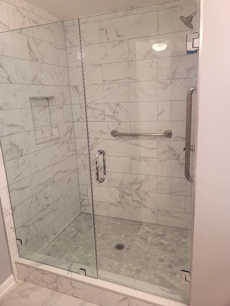 A bathroom with a walk in shower with a glass door.