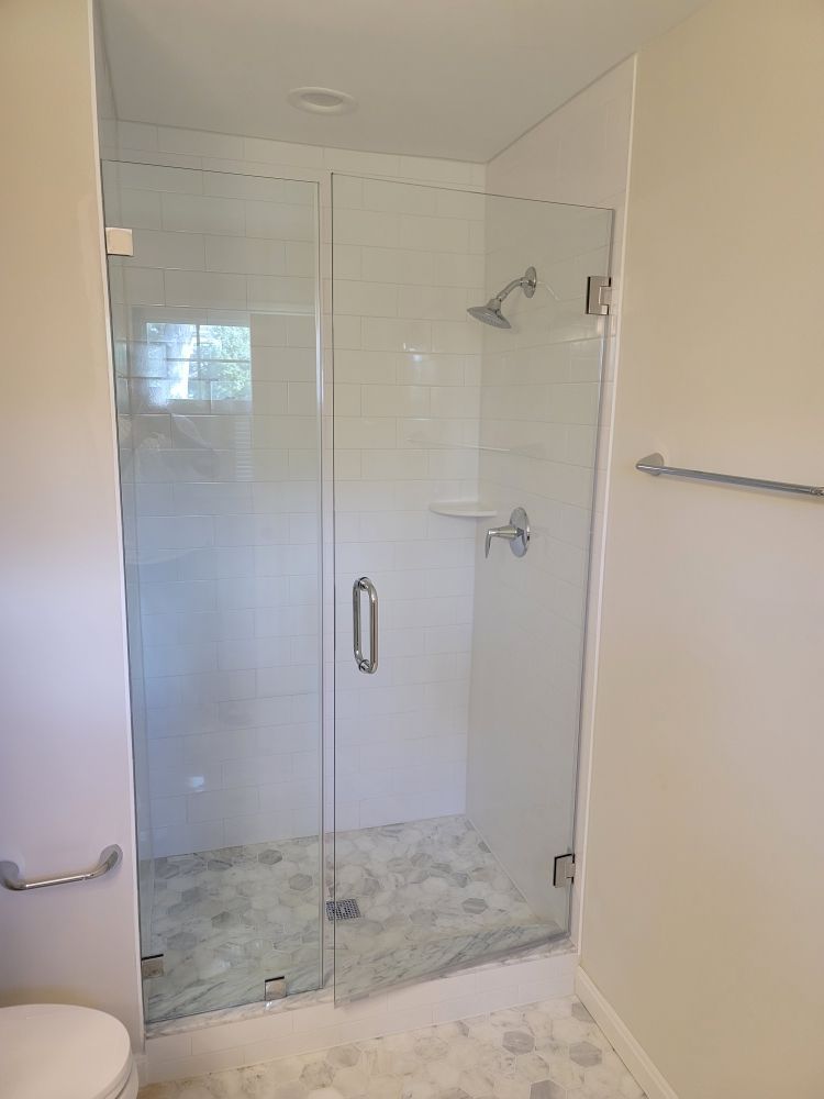A bathroom with a glass shower door and a toilet.