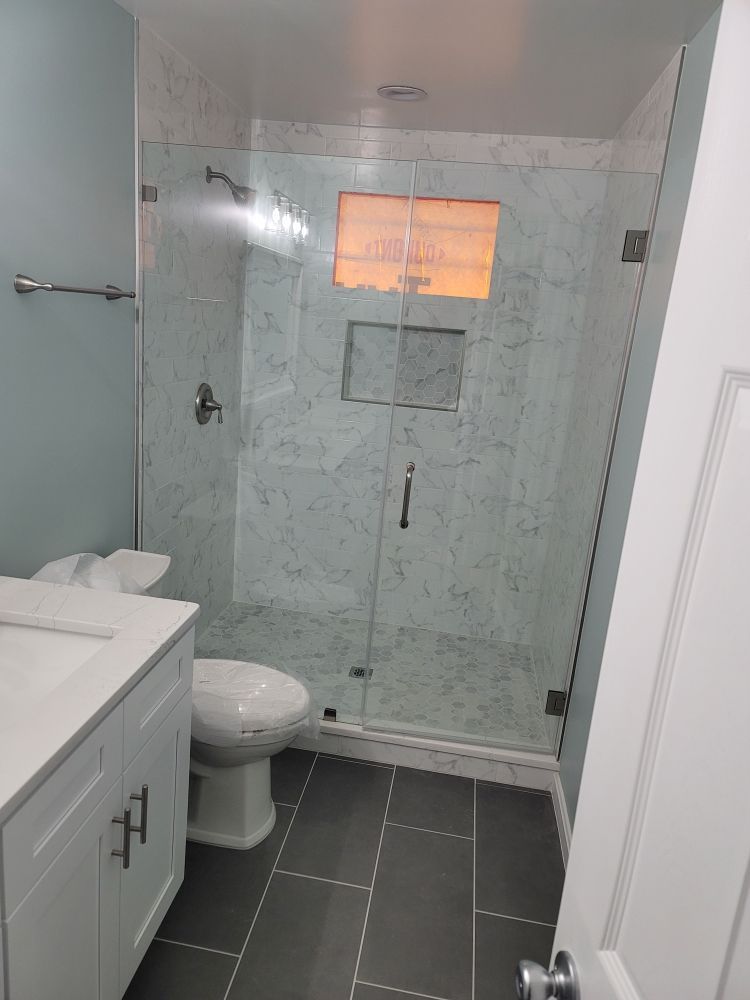 A bathroom with a toilet , sink and shower.