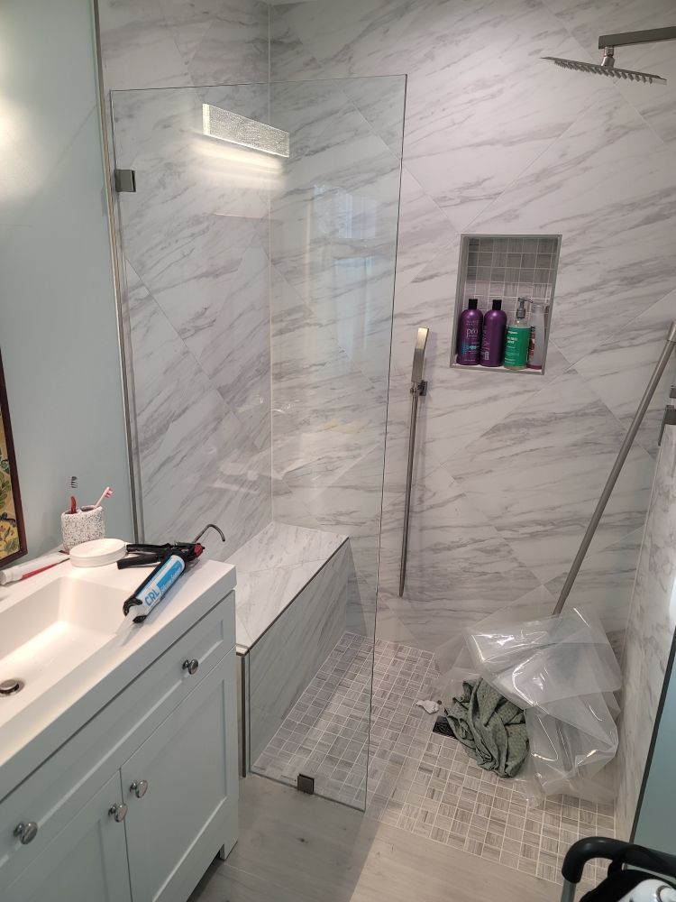 A bathroom with a walk in shower and a sink.
