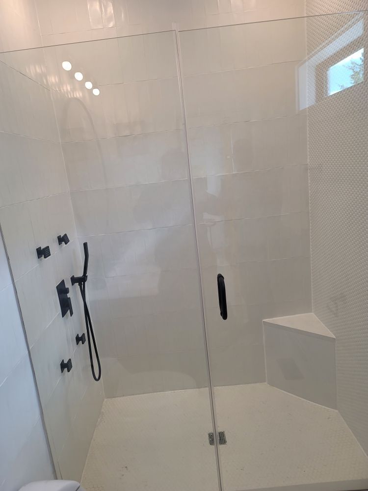 A bathroom with a walk in shower with a glass door.