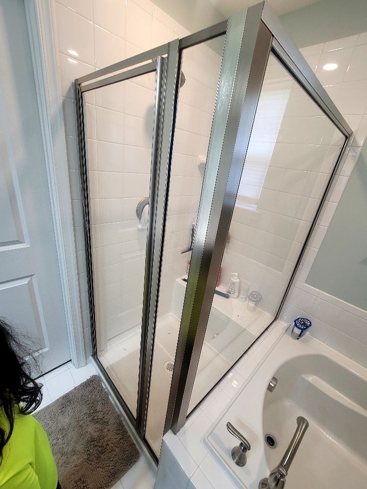 A woman is standing in a bathroom next to a tub and shower.