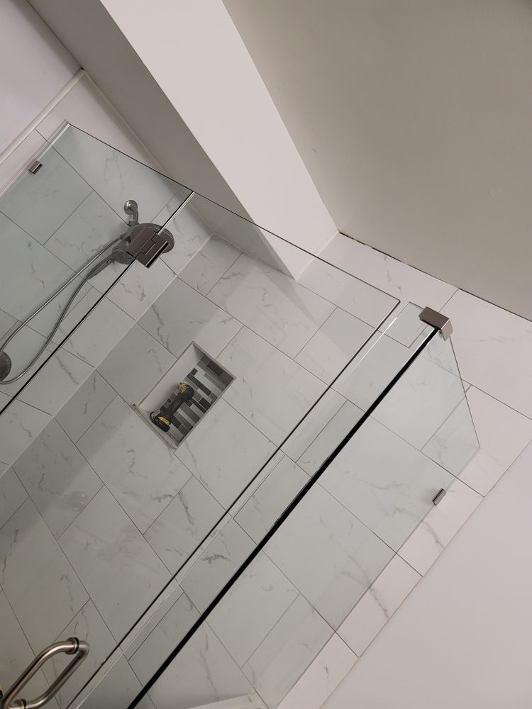 A bathroom with a walk in shower with a glass door