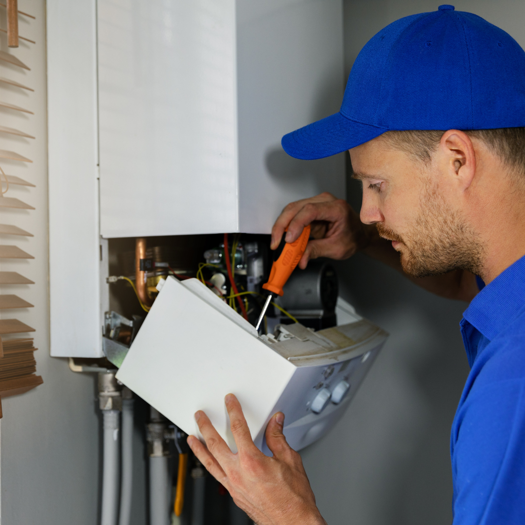 A man in a blue hat is working on a boiler