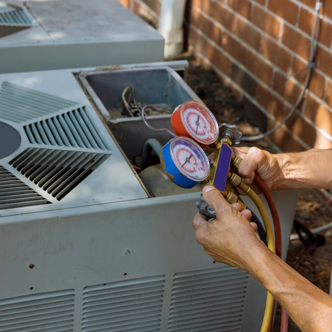 A person is working on an air conditioner with two gauges on it