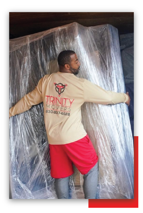 Man Hugging Huge Sofa With Plastic Cover — New Braunfels, TX — Trinity Movers