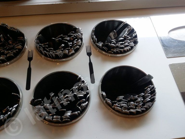 Sei contenitori rotondi e scuri con sagome di utensili; riempiti con oggetti scuri e testurizzati.