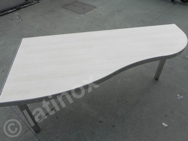 Tavolo bianco con bordi curvi su gambe in metallo, su sfondo di cemento grigio.