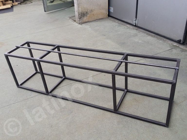 Struttura rettangolare in metallo, ideale per una panca o un espositore. Metallo grigiastro su superficie in cemento.