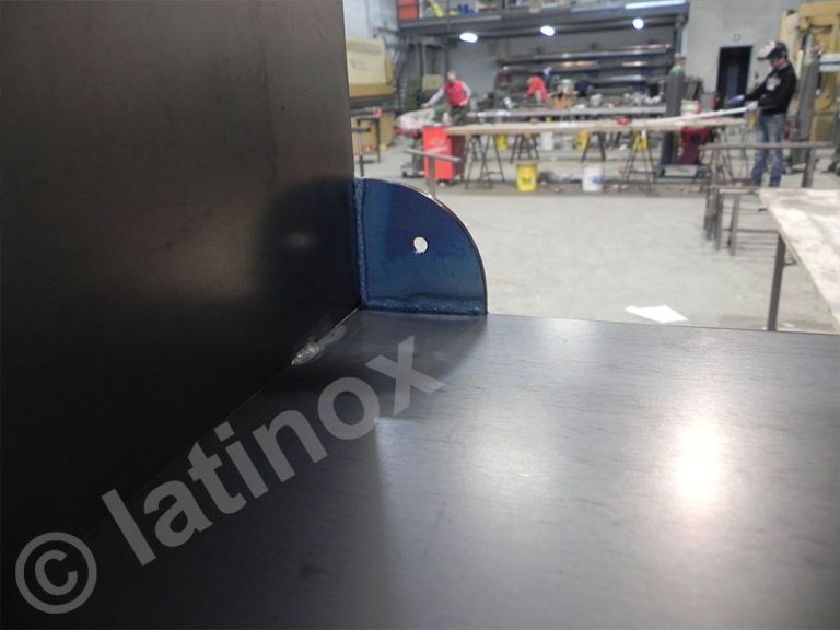 Lamiere nere con una staffa angolata blu scuro in un'officina.