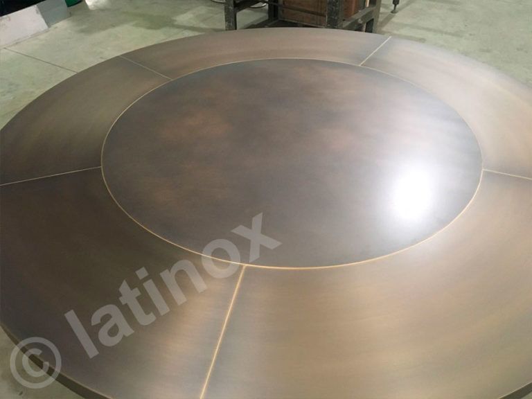 Tavolo circolare in metallo con inserto centrale che mostra le linee di saldatura.