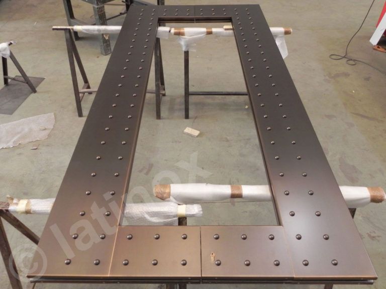 Sezioni del telaio della porta in metallo color bronzo con rivetti, sostenute da cavalletti.