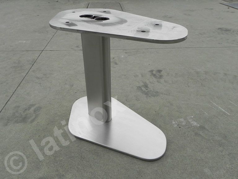 Base per tavolo in metallo con piano e base a forma di lacrima, collegati da una colonna rettangolare, su una superficie in cemento.