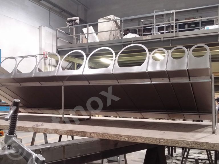 Attrezzatura industriale in acciaio inossidabile con aperture ad arco, posizionata su un piano di lavoro.