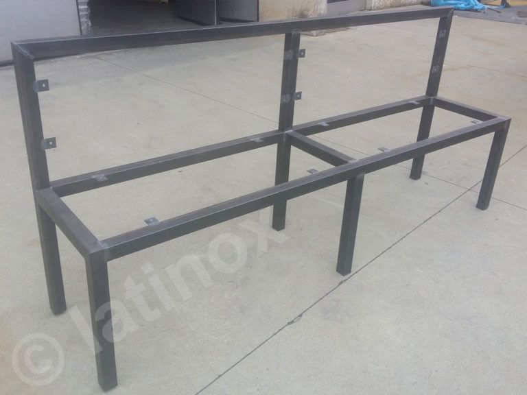 Struttura della panca in metallo, grigia, con supporto per schienale e seduta, appoggiata su una superficie in cemento.