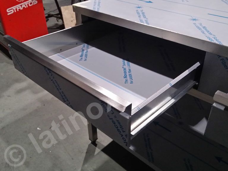 Cassetto in acciaio inox, parzialmente aperto, integrato nel piano di lavoro.