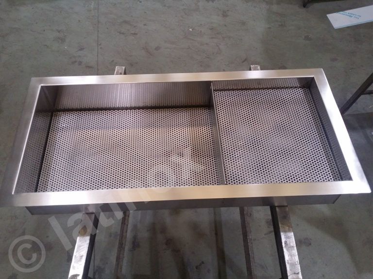 Lavello rettangolare in acciaio inox con fondo in grigliato e bordo laterale, appoggiato su telaio metallico.